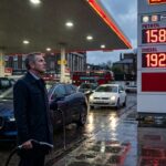 A worried British motorist looking at a digital petrol station sign showing diesel prices at 192p per litre.